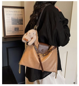 Detail view of khaki large tote bag featuring flip cover and plush rabbit charm accessory