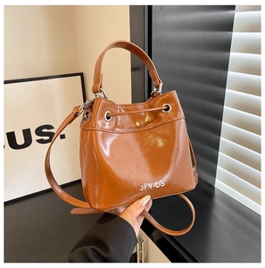 Detail of brown glossy bucket bag with drawstring closure and silver JFY-DS metal logo