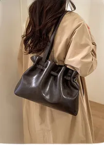Detail of dark brown pleated tote bag with glossy finish and Korean text lettering