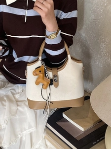 Chic two-tone beige and camel leather tote bag with horse charm shown in a cozy setting