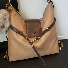 Detail of vintage tote bag with two-tone brown stitching, metal hooks and pompom charm