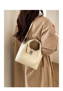 Close-up of cream leather bucket bag showing lychee grain texture and silver twist lock