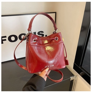Detail of burgundy bucket bag featuring oil-wax leather texture and drawstring closure