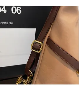 Detail of adjustable leather strap with gold buckle and chain for a casual tote bag