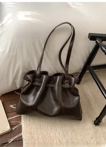 Close-up of deep brown pleated tote bag in glossy leather with Korean lettering detail