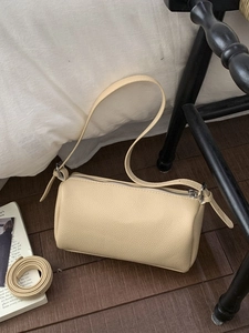 Minimalist cream cylinder pillow bag in lychee texture leather with dual straps