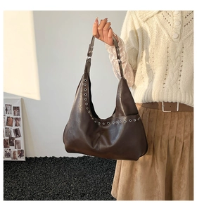 Detail of dark brown hobo bag featuring glossy leather and silver metal eyelets