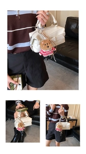 Borsa Boston bianca con ciondolo a orsetto e trama litchi in un contesto di vita quotidiana