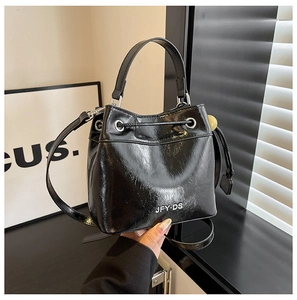 Detail of a black glossy bucket bag featuring JFY DS logo and silver hardware accents