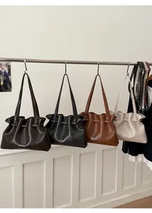 Detail view of stylish pleated leather tote bags in brown, black, tan, and beige