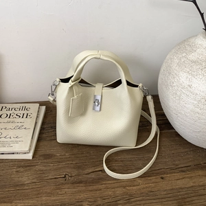 Detail of cream white lychee pattern bucket bag with silver twist lock and leather strap