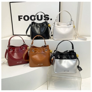 Collection of textured bucket bags in five colors on a tiered display stand