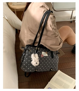 Close-up of grey felt tote bag with white polka dots, leather straps and plush puppy charm