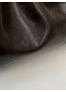 Detailed shot of dark brown wrinkled leather texture with silver Korean logo plaque