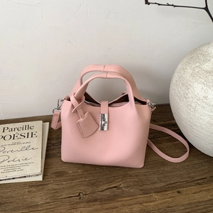 Close-up of pink litchi grain bucket bag with silver metal lock on a rustic wood table