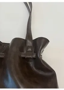 Detail of dark brown leather tote showing reinforced stitching on the shoulder strap
