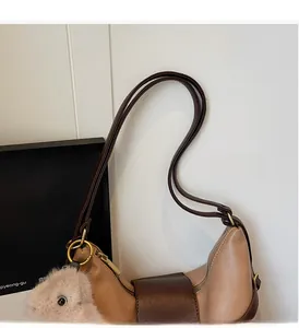 Detailed close-up of oatmeal leather tote handle with gold hardware and plush charm