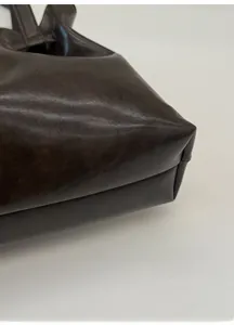 Macro shot of dark brown leather tote bag highlighting fine texture and seam details