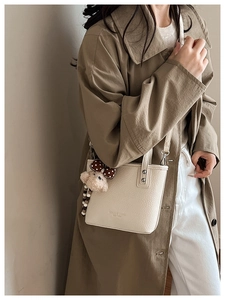 Detail of cream bucket bag with lychee texture and cute brown plush bear charm