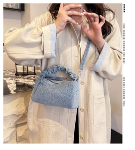 Détail du sac polochon en denim bleu avec poignée froncée et bandoulière amovible