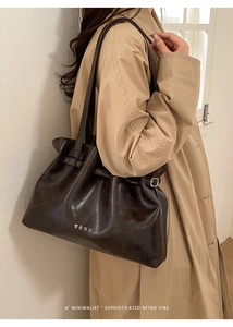 Detail of dark brown pleated tote bag featuring high-gloss leather and metallic buckle