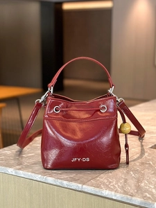 Fashionable burgundy leather bucket bag with glossy finish and stylish wood bead charm