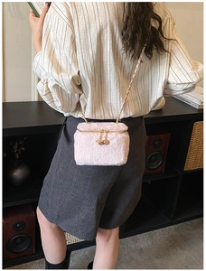 Detail of a pink fuzzy faux fur mini box bag featuring a gold chain strap and zipper