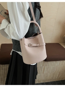 Detail of light pink lychee pattern bucket bag featuring a silver metal buckle and strap