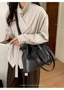 Close-up of black leather tote bag with drawstring details and elegant side metal buckle