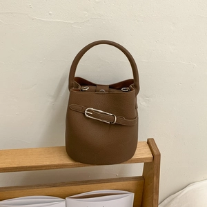 Détail du sac seau en cuir grainé marron avec boucle métallique argentée et texture