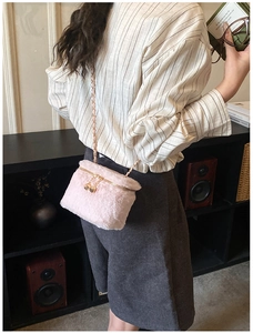 Detailed view of pink faux fur mini bag featuring a gold chain and unique dice pendant