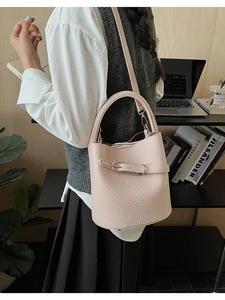 Detail of light pink lychee pattern bucket bag with silver buckle worn by a model
