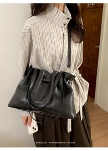Detail showing the pleated closure and white Korean text on this black leather tote bag