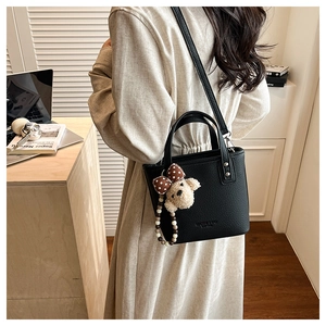 Photo lifestyle d'un sac seau noir en cuir avec pendentif de chiot en peluche mignon