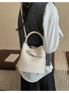 Detail of off-white lychee texture leather bucket bag with metal buckle and strap