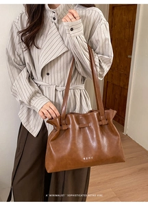 Detail of vintage brown pleated leather tote bag with soft oily finish and brand logo