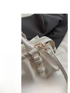 Details goldener Metallbeschläge und plissierter Ledertextur auf beiger Boston Bag