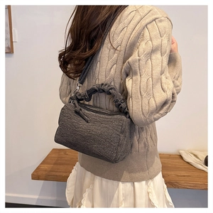 Détail d'un sac bandoulière en tweed gris foncé avec poignée froncée et bandoulière cuir
