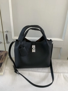 Minimalist black litchi grain leather bucket bag with silver lock and shoulder strap