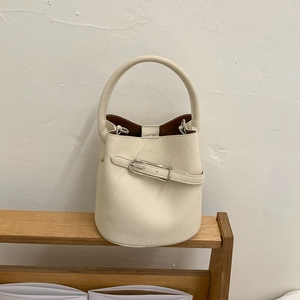 Gros plan d'un sac seau en cuir litchi blanc crème avec boucle en métal argenté