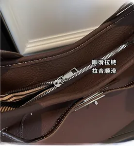 Close-up of smooth silver zipper and lychee grain leather with white stitching detail