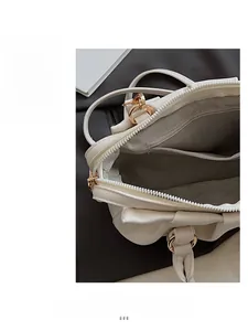 Detail der cremefarbenen Ledertasche mit Reißverschluss, Fischgrätfutter und Goldbeschlägen