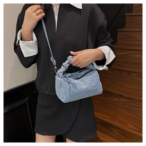 Détail du sac en denim bleu clair avec poignée froncée et accents métalliques argent
