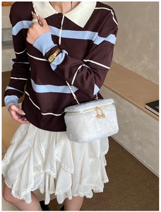 Close-up of white plush mini box bag with gold chain strap on a stylish outfit