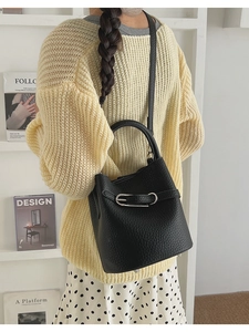Close-up of black lychee pattern bucket bag with silver metal buckle in a lifestyle setting