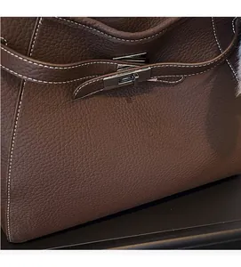 Detail of dark brown lychee leather handbag with gunmetal turn-lock and white stitching