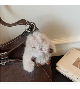 Detail of soft faux fur rabbit charm attached to a brown leather tote bag with silver ring