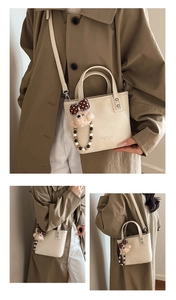 Detailed view of beige pebble leather bucket bag with cute bear charm and chain
