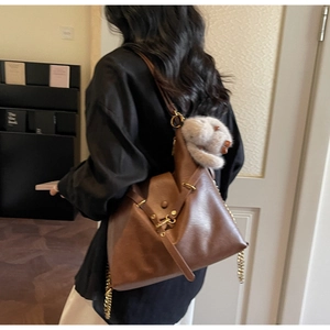 Detail of brown leather tote with gold hardware and a grey plush rabbit charm detail