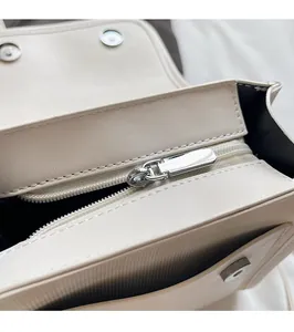 Detail of silver zipper hardware and magnetic closure on a creamy white tote bag